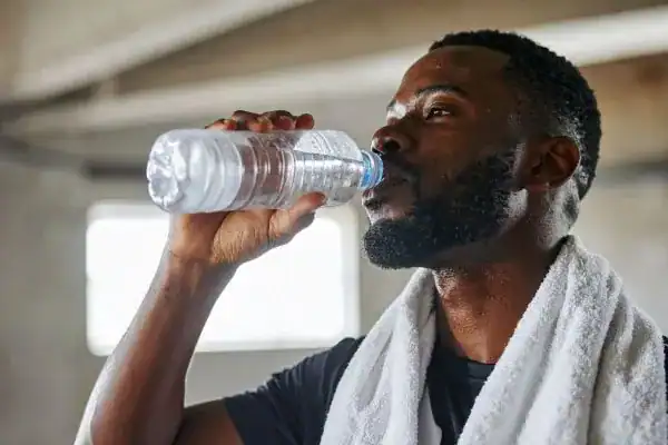 Image of man drinking water to improve hydration Harrogate after work out.